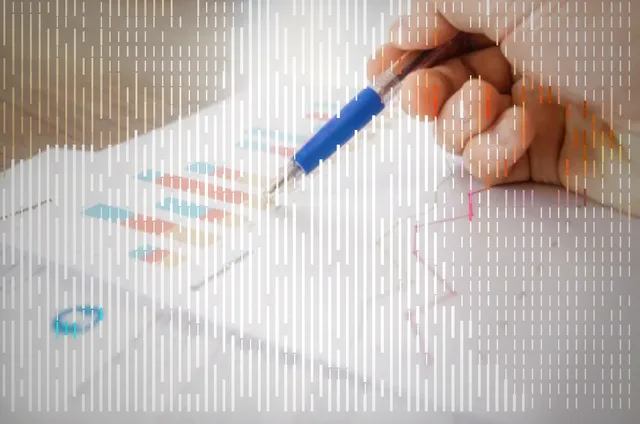 Hand with pen reviewing printed charts