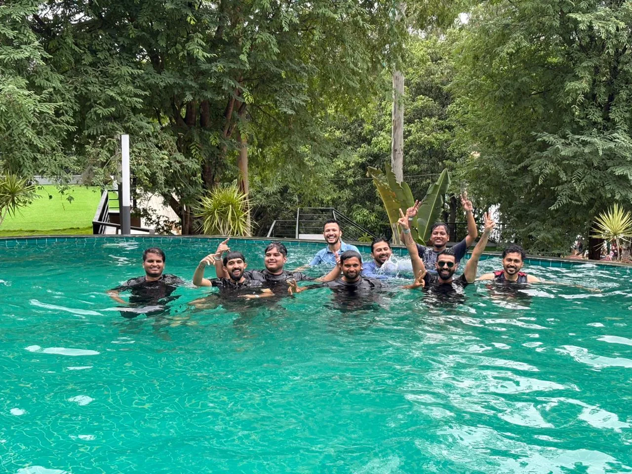 Team members in the resort pool, waving at the camera