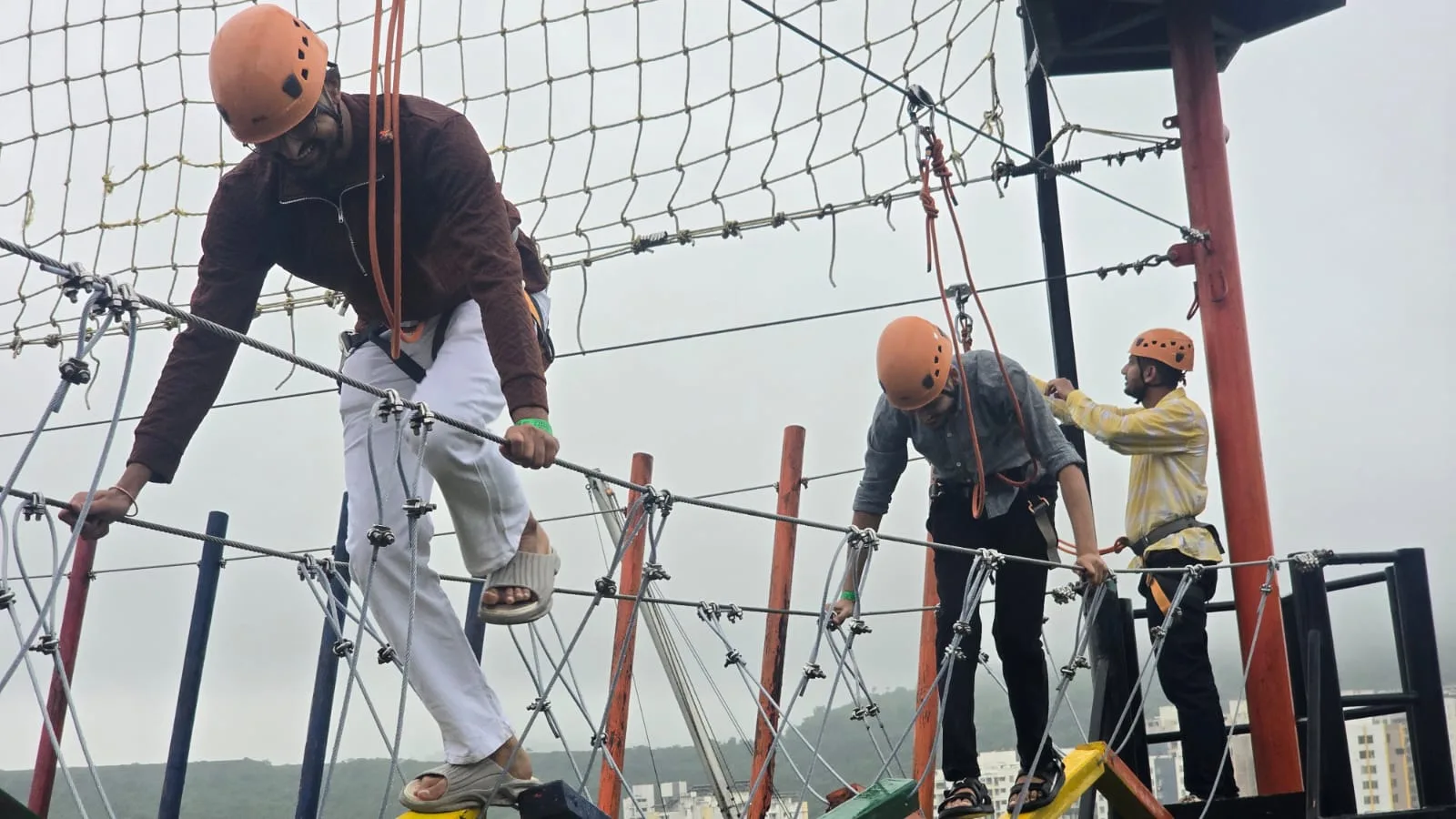 Team members in helmets and harnesses crossing a high rope course